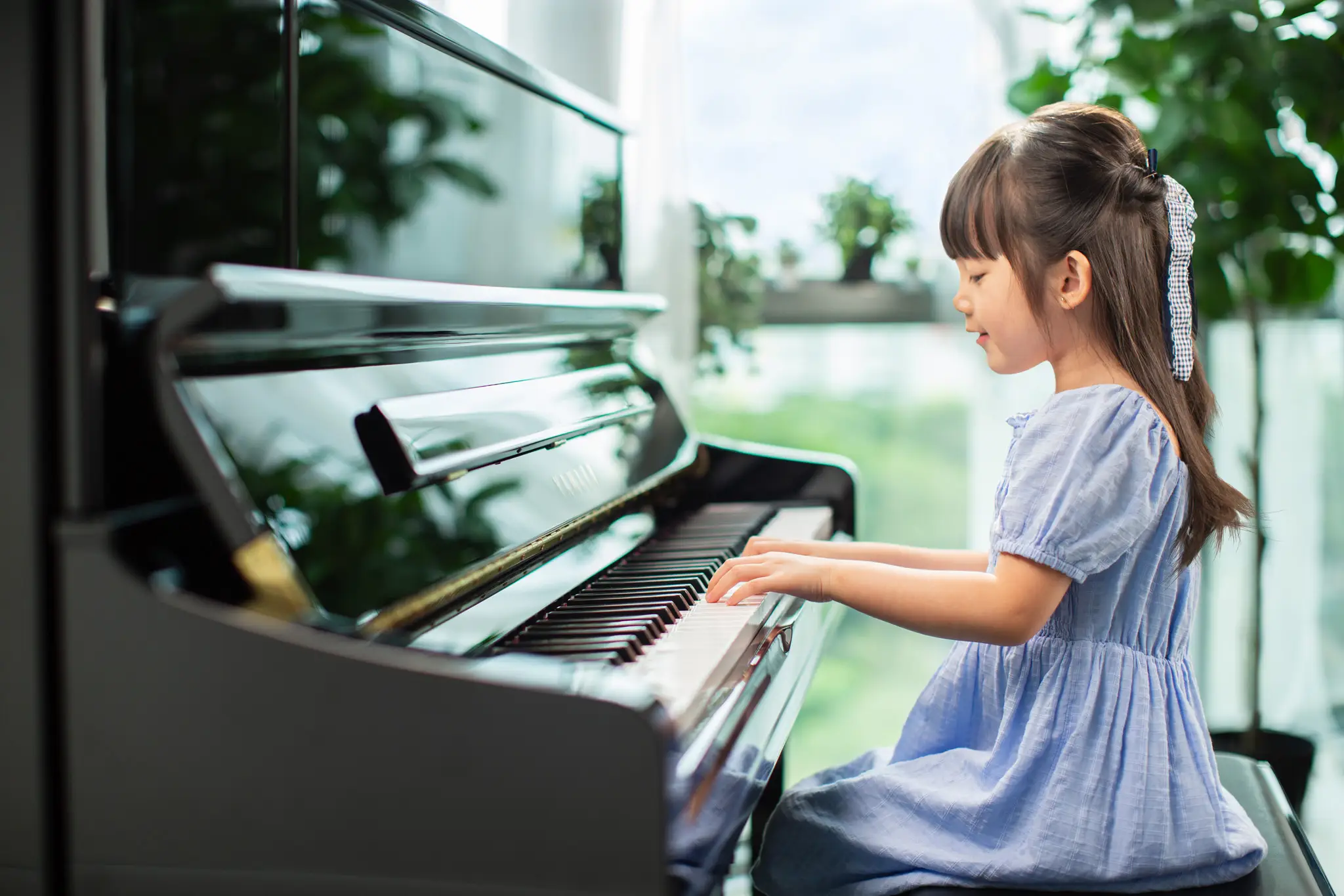 Young girl learning to play a Yamaha piano in a bright, nurturing music environment